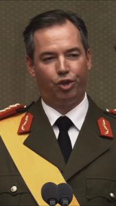 Grand Duke Guillaume in ceremonial uniform with yellow sash, speaking at microphones